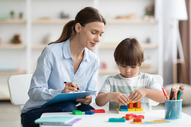 speech-therapist-working- a-child-with autism Speech therapist supporting communication and play skills with a young child